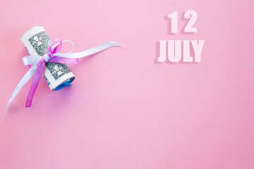 calendar date on pink background with rolled up dollar bills pinned by pink and blue ribbon with copy space. July 12 is the twelfth day of the month