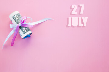 calendar date on pink background with rolled up dollar bills pinned by pink and blue ribbon with copy space. July 27 is the twenty-seventh day of the month