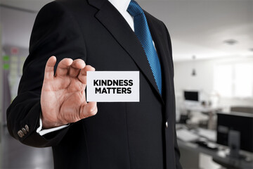 Businessman shows a business card with the message kindness matters. Kindness in the workplace