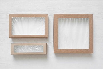 Small packing food cardboard boxes with transparent cover on the white table background.