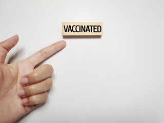 Healthcare Concept - VACCINATED text on wooden block background. Stock photo.