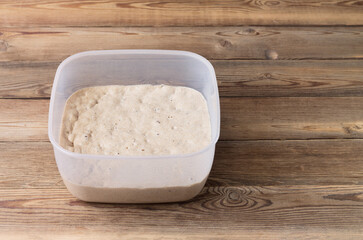 Rye sourdough on flour sourdough in a container on a wooden table. Fermentation.