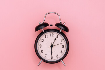 Black alarm clock on pink background