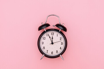 Black alarm clock on pink background