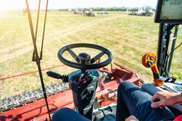 Unmanned autonomous harvester on the field. View from the cockpit. The driver does not keep his hands on the steering wheel	

