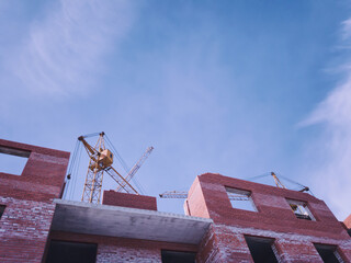 residential buildings under construction. unfinished house and yellow tower crane