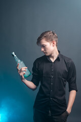 Guy looks at a bottle of smoke on a gray background