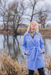 Woman in violet coat, colorful scarf, portrait of blonde nice lady at city park, trendy concept