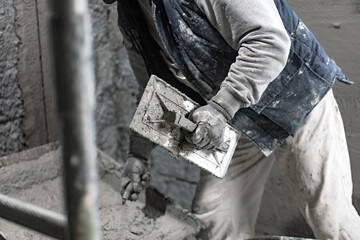 Real construction worker working on a wall inside the new house.