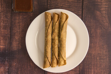 Traditional Mexican food, golden meat tacos (flautas) with red sauce.