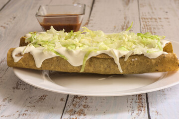 Traditional Mexican food, golden meat tacos (flautas) with red sauce.