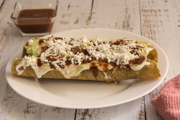 Traditional Mexican food, golden meat tacos (flautas) with red sauce.
