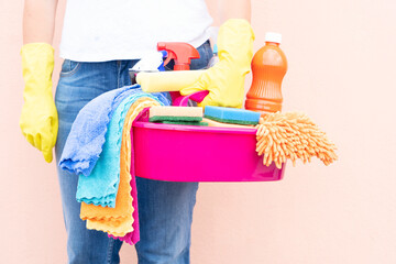 caucasian woman holding basin with cleaning supplies
