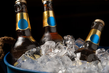 close up of beer in ice bucket in dark tones