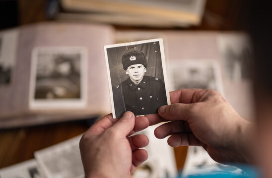 Male hands are holding an old army photograph.