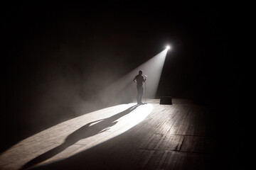Stand up comedian on stage in the beam of light.