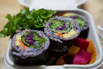 Vegan food in paper container with rice, seaweed, vegetable and vegan cheese