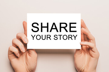 Female hands hold card paper with text Share your story on a yellow background. Business and finance concept