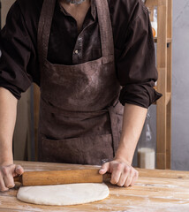 Baker man kneading or making dough or bread cooking. Bakery concept and wooden table