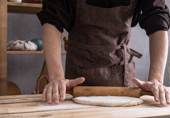 Baker man kneading or making dough or bread cooking. Bakery concept and wooden table