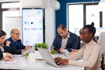 African business owner entrepreneur planing strategy in briefing conference planing company room. Diverse colleagues working in background. Multiethnic coworkers planning new financial project.