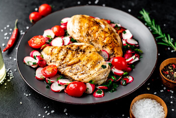 Grilled chicken breast and salad with fresh vegetables, tomatoes and radishes in a plate Chicken meat with salad. Healthy food on stone background