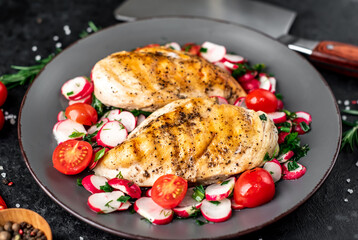 Grilled chicken breast and salad with fresh vegetables, tomatoes and radishes in a plate Chicken meat with salad. Healthy food on stone background