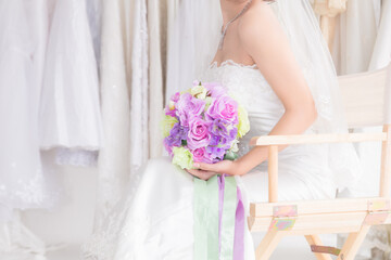 Obraz na płótnie Canvas Beautiful Asian bride in wedding dress concept, happy girl hold flowers bouquet dream to her wedding date plan to shopping, woman in bridal dress with colorful floral bouquet in fitting room
