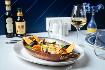 Spanish seafood paella in a pan with a glass of white wine
