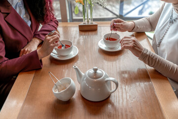 Cups of black tea in the hands of men and women. on a wooden background. with copy space. top view