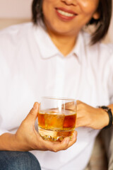 Smiling pretty girl with white shirt taking whiscky on the couch
