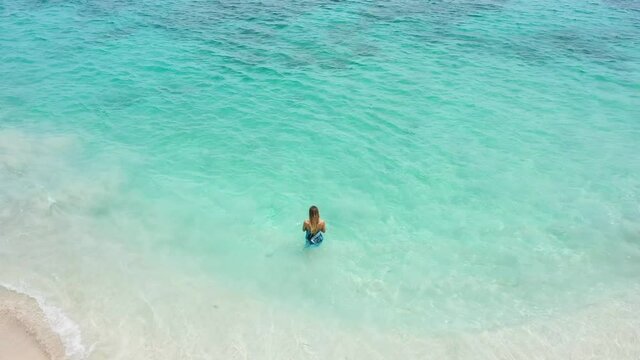 beautiful view of the beach with azure blue water and white sand a beautiful blonde girl enters the water opening ocean view