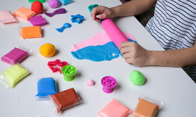 Children's hands play with plastic multi-colored mass. Modeling and development of fine motor skills.