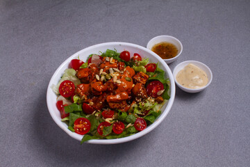 Healthy green salad with deep fried chicken isolated on gray background