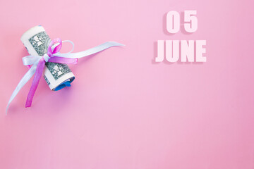 calendar date on pink background with rolled up dollar bills pinned by pink and blue ribbon with copy space.  June 5 is the fifth  day of the month