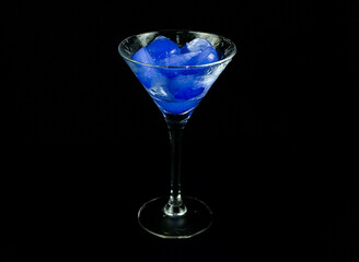 A tequila glass with blue strawberry ice.