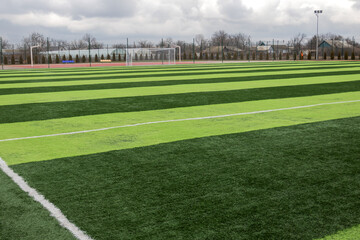 Fototapeta na wymiar Artificial green grass on a professional soccer field. Outdoor artificial soccer field awaiting players' exit