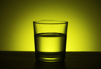 A glass with water at yellow background