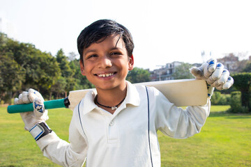 Boy in cricket uniform holding a cricket bat 