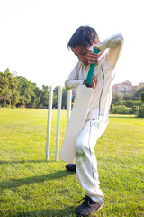 Young boy batting in protective gear during a cricket