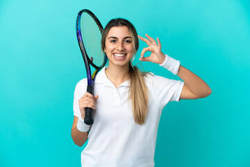 Young woman tennis player isolated on blue background showing ok sign with fingers