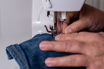 Hands of an older woman, doing sewing with her sewing machine.