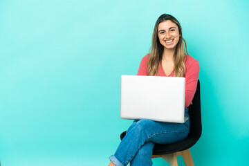 Young caucasian woman sitting on a chair with her pc isolated on blue background keeping the arms...