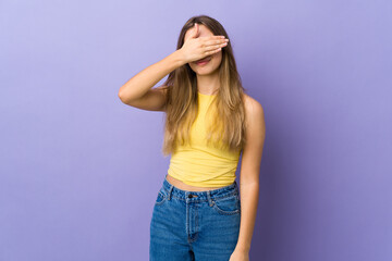 Young woman over isolated purple background covering eyes by hands. Do not want to see something
