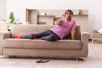 Obraz premium Young man watching tv at home during pandemic