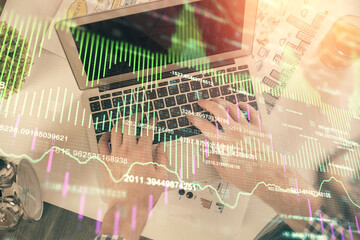 Double exposure of man's hands typing over laptop keyboard and forex chart hologram drawing. Top view. Financial markets concept.