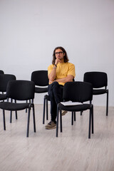 Young male student waiting for teacher in the classroom