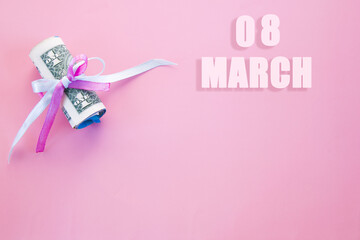 calendar date on pink background with rolled up dollar bills pinned by pink and blue ribbon with copy space. March 8 is the eighth day of the month