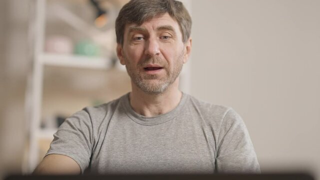 Portrait of yogi coach talking at laptop explaining breathing exercise in online training. Handsome middle aged Caucasian man coaching yoga in social media. Wireless workout and sport concept.
