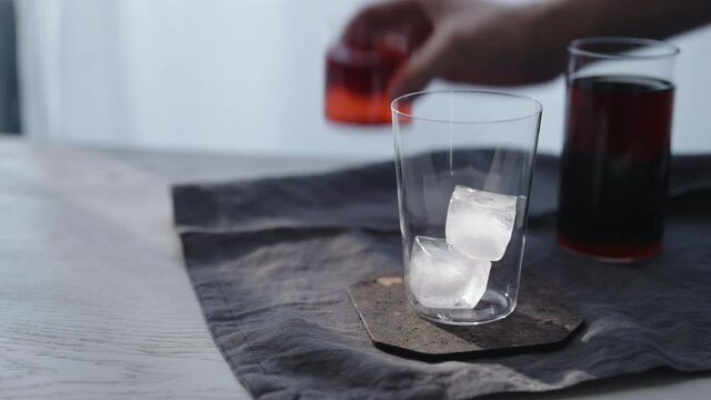 Tracking dolly shot of making cocktail aperetivo in tumbler glass with window on background